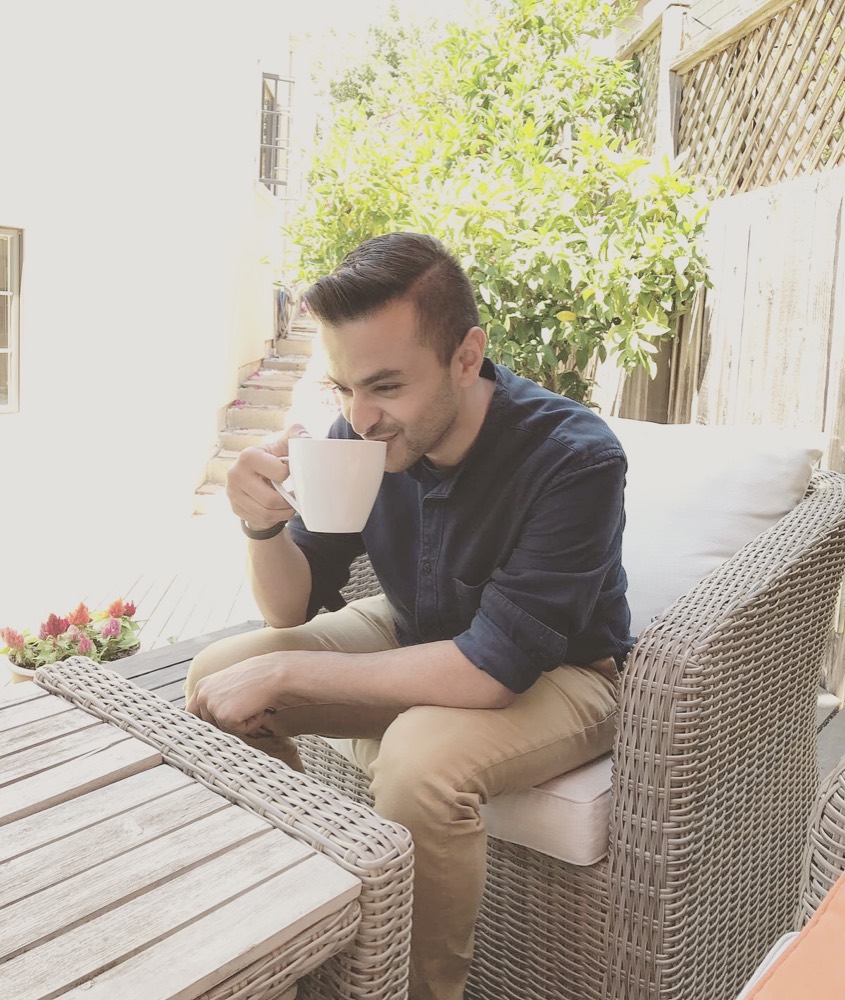 Omar enjoying a cup of coffee on a sunny patio